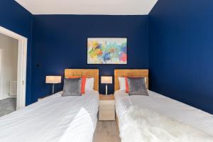 巴罗弗内斯Stylish Luxury Large 4BR KingBed的蓝色墙壁客房的两张床