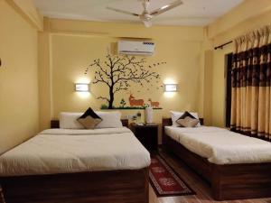 索拉哈Hotel Mirage Sauraha的卧室配有两张床,墙上挂有树壁画