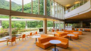 会津若松Ooedo Onsen Monogatari Higashiyama Grand Hotel的大堂设有橙色椅子和桌子以及窗户。