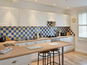 塞拉戴克Nautilus Cottage的厨房配有白色橱柜和木制台面
