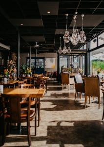 KapelleMotel-Restaurant-Grand Cafe de Caisson的餐厅设有木桌、椅子和吊灯。