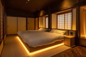 萩市萩之宿巴旅馆的一间卧室配有一张带灯光的床