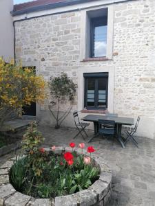 Soisy-sur-ÉcoleChez Marylene的一座建筑前带桌子和鲜花的庭院