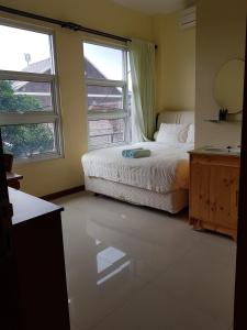 万隆G10 Guest House Near Asia Afrika Bandung的一间卧室设有一张床和两个大窗户