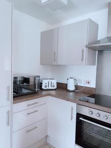 曼彻斯特Shared Modern Apartment Double Bedroom With Attached Bath的厨房配有白色橱柜和炉灶烤箱。