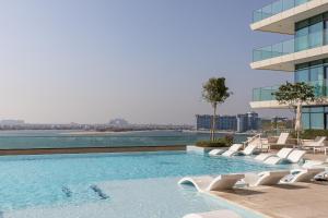 迪拜Sea View with Private Beach Access! 3BR & Maid Rm的一座带白色椅子的游泳池和一座建筑