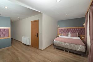 伊斯坦布尔黑珍珠酒店的一间卧室配有一张大床和紫色床头板