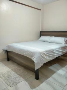 纳纽基Rovers Apartment的配有白色床单和枕头的宿舍间内的一张床位