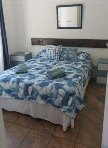贝蒂湾Streams Cottage的一间卧室配有一张带蓝色毯子和镜子的床