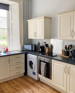 莫珀斯Meldon Cottage in Morpeth, Northumberland的厨房配有白色橱柜、洗衣机和烘干机