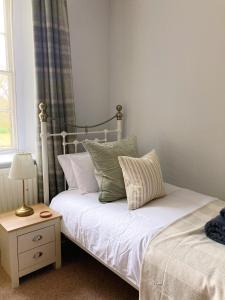 莫珀斯Meldon Cottage in Morpeth, Northumberland的一间卧室配有一张床和一张带台灯的桌子