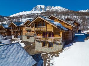 瓦尔Chalet Mountainside avec sauna et jacuzzi à 200m des pistes的雪中的一个圆木度假屋,背景是群山