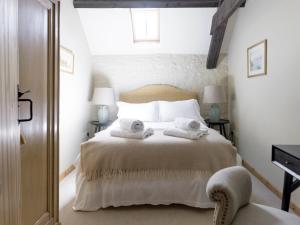 Ampney CrucisThe Long Barn的一间卧室配有带毛巾的床