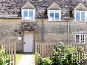 Ampney CrucisThe Long Barn的砖屋,有白色的门和栅栏