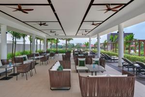 马六甲Courtyard by Marriott Melaka的户外餐厅设有桌椅,种植了棕榈树