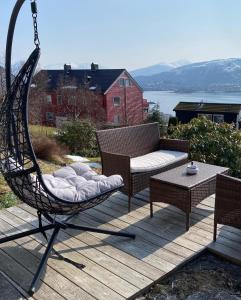 奥勒松Great place with view to the mountains and fjord的秋千椅和甲板上的桌子