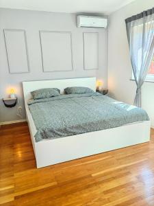 班约勒Zelena oaza 300 metara od mora的白色卧室内的一张白色床,铺有木地板