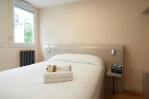 南特佩提杜肯酒店 的卧室配有白色的床和电视。