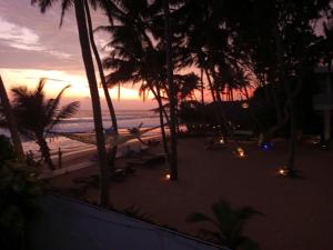 希克杜沃蓝色海洋别墅酒店的棕榈树和吊床海滩上的日落