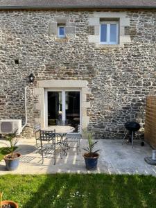 塔登La maison d'André的石头建筑前方的带桌椅的庭院