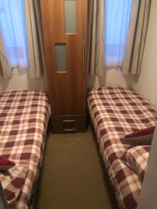 桑当First Steps Caravan Rentals的一间卧室设有两张床、一个橱柜和窗户。