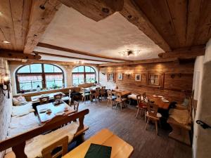 贝希特斯加登Pension Etzerschlössl的餐厅铺有木地板,配有桌椅