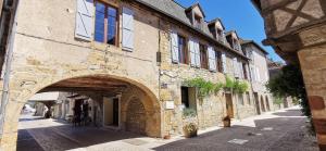 布里特努Maison Pierre Loti, gîte historique et spacieux en vallée de la Dordogne的街道上带有拱门的石头建筑