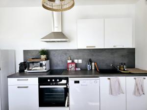 蒙特Lakeside Provence - Appartement 4 étoiles face au lac de Monteux的厨房配有白色橱柜和黑烤箱。