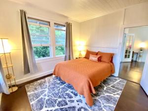 希洛YOUR HILO HOMEBASE - Lovely 3 Bedroom in Heart of Hilo with AC!的一间卧室配有一张带橙色毯子和窗户的床。