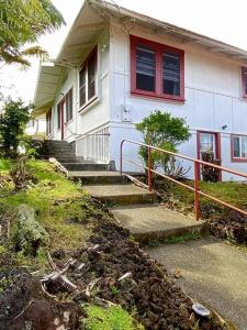 希洛YOUR HILO HOMEBASE - Lovely 3 Bedroom in Heart of Hilo with AC!的白色的房子,有红色的窗户和楼梯