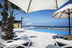 阿里卡阿里卡泛美酒店的一个带椅子和遮阳伞的游泳池以及大海