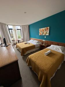 伊塔蒙蒂Hotel São Gotardo的酒店客房设有两张床和蓝色的墙壁。