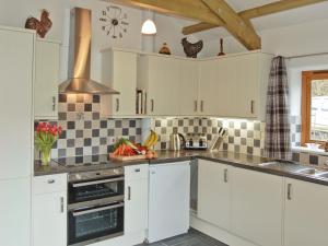 博德明斯戴普斯乡村别墅的厨房配有白色橱柜和黑白瓷砖