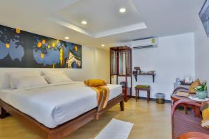 清迈Chedi Home -SHA Extra Plus的卧室配有一张白色床,墙上挂有绘画作品