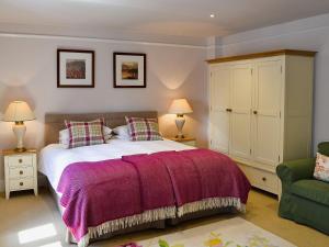 Luxulyan普里多乡村别墅的一间卧室配有一张大床和紫色毯子