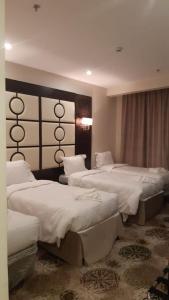 麦加فندق البيرق的酒店客房,配有3张带白色床单的床