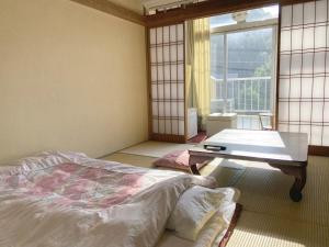 鸭川市吉冈日式旅馆的一间卧室配有一张床、一张桌子和一个窗户。