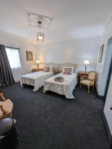 ToodyayToodyay Manor的酒店客房带两张床和一张桌子以及椅子。