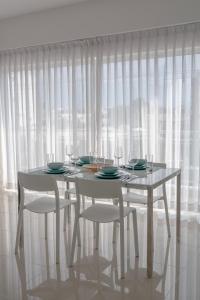 Los PradosPalmer Suites的白色的桌椅和白色的窗帘