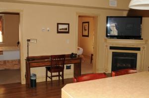 Peace RiverThird Mission Heritage Suites的客厅配有电视和带壁炉的书桌。