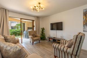 德班67 The Shades - Luxury Apartment in Umhlanga - Airconditioning throughout and Inverter的客厅配有沙发、椅子和电视