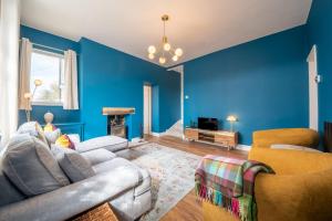马特洛克Corner Cottage的客厅拥有蓝色的墙壁,配有沙发和椅子