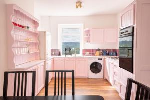 马特洛克Corner Cottage的粉红色的厨房配有白色橱柜和洗碗机