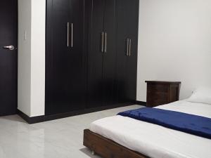 派帕Comoda casa para descansar en Paipa & excelente ubicacion的一间卧室配有黑色橱柜和一张带白色床单的床。