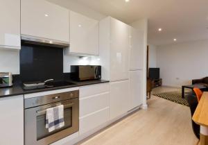 伦敦2-Bed Apartment only 15 mins from Central London的厨房配有白色橱柜和炉灶烤箱。