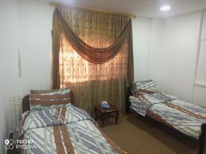 乌姆盖斯Baiet AL-Deafah Guest house的客房设有两张床和一个带窗帘的窗户。