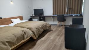 秩父市Basic Hotel Chichibu的一间卧室配有两张床、一张桌子和两把椅子