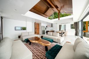 苏梅岛Samui Privacy Modern Luxury Seaview Natural Rainforest Infinity Pool Villa的客厅配有白色家具和桌子