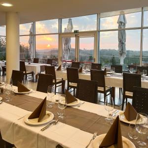 多博沃Hotel Kozana的餐厅设有白色的桌椅和窗户。