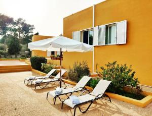 Sant Francesc de s'EstanyBonita Casa con piscina privada y amplio jardin的大楼前的四把椅子和一把伞